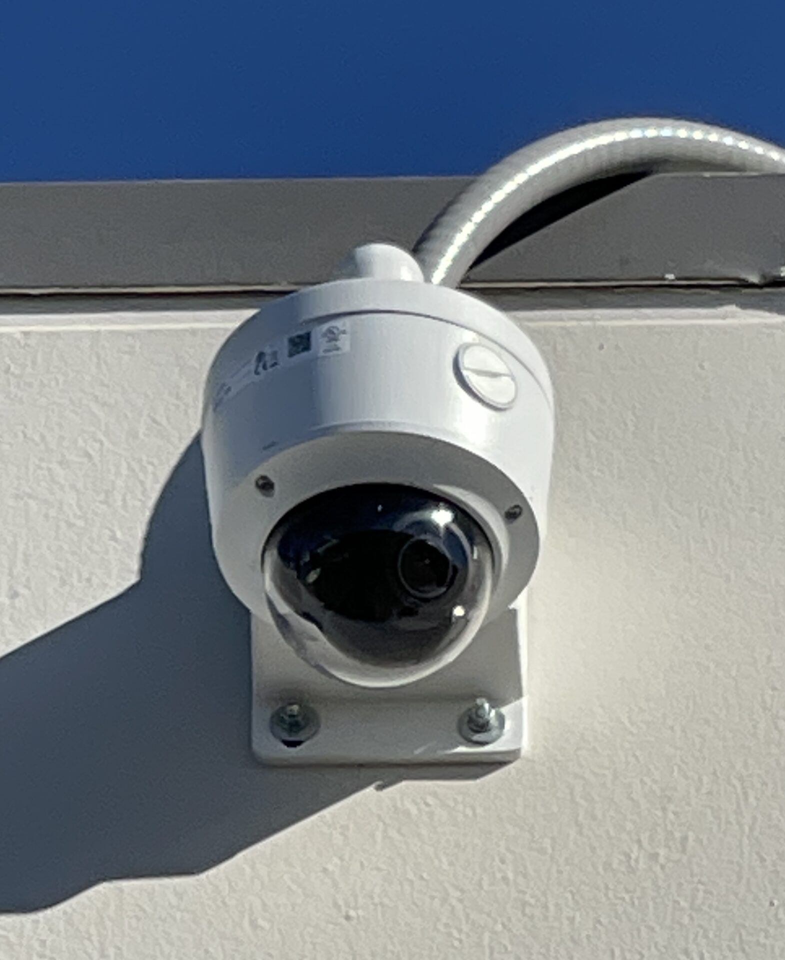 A white security camera mounted on the side of a building.